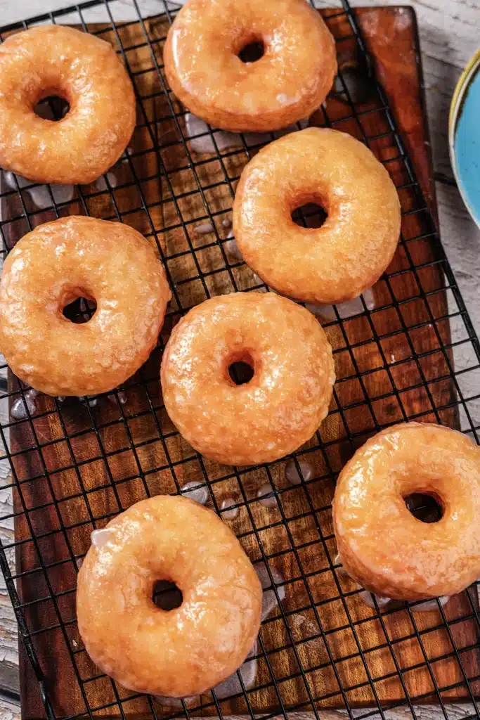 Copycat Krispy Kreme donuts on a cooling rack over a dark wooden board
