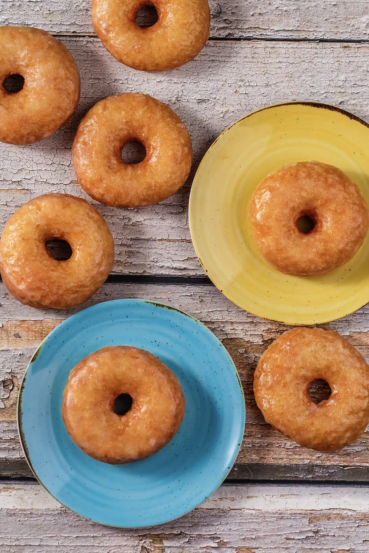 Homemade Krispy Kreme donuts on blue and yellow plates seen from directly above