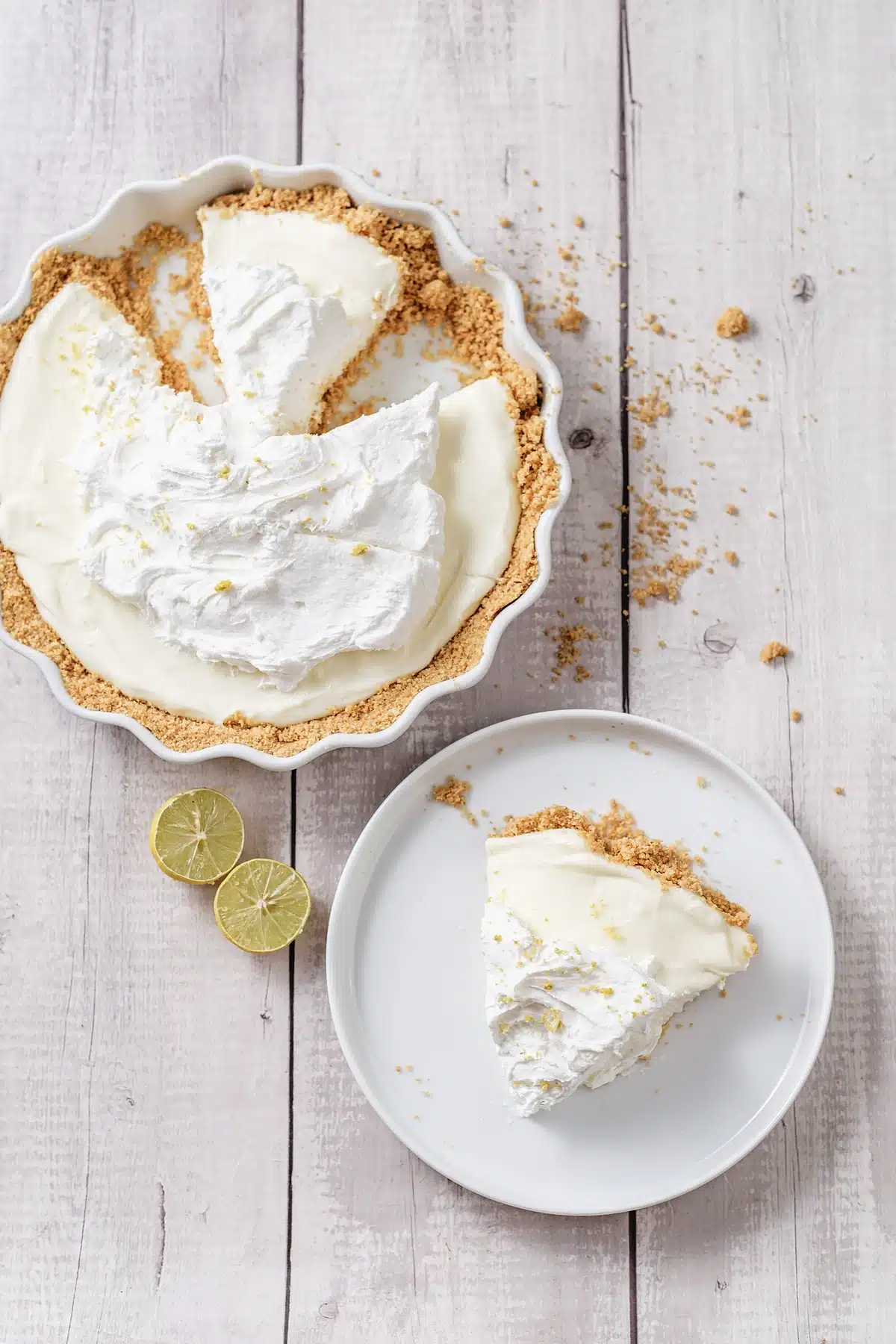 Lemon icebox pie with a slice on a small plate and two lime rounds