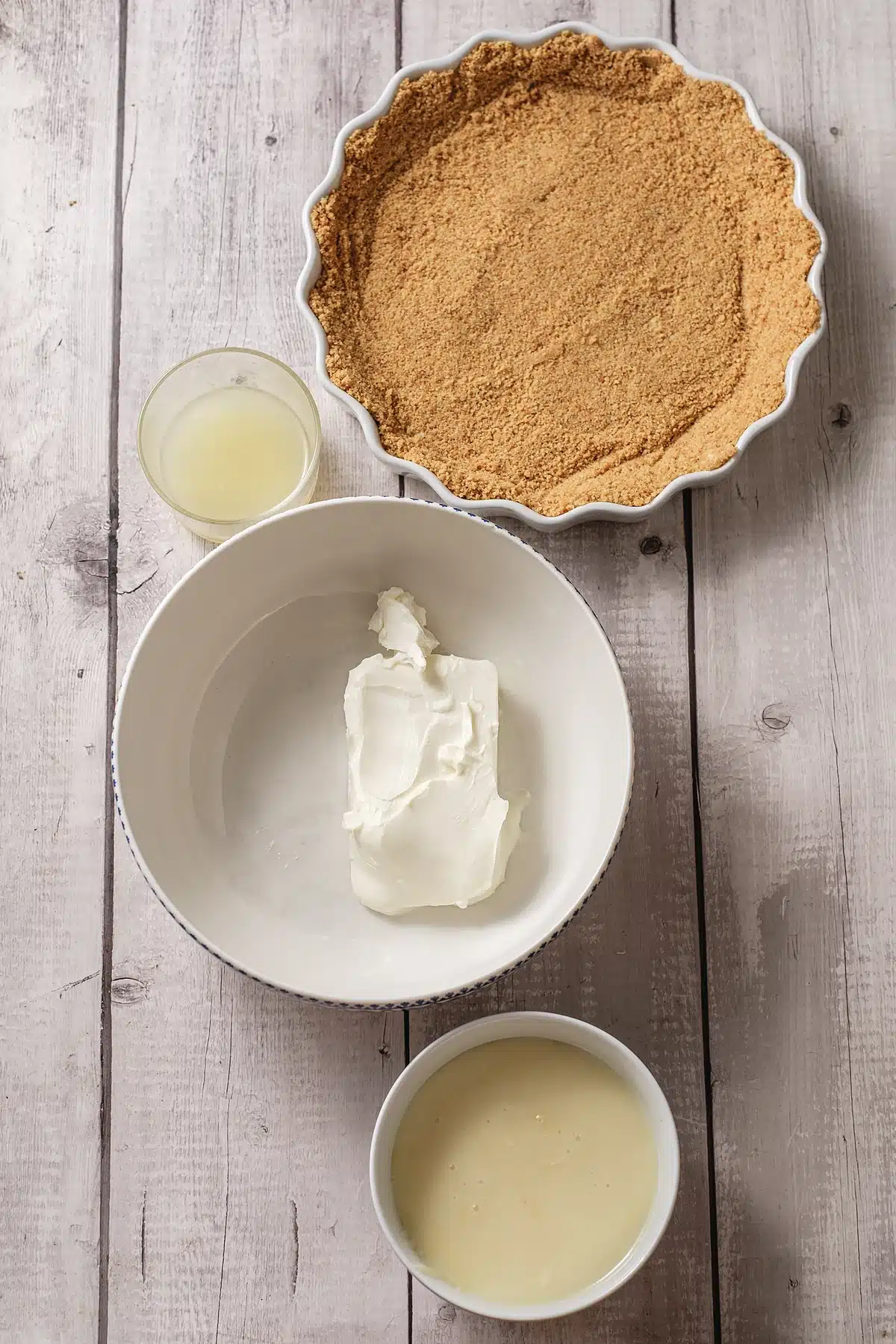 Graham crumbs pressed into a fluted dish with cream cheese, juice and milk