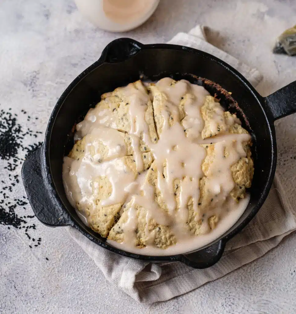 Lemon poppy seed scones baked as one glazed round in a cast-iron skillet, seen from directly above