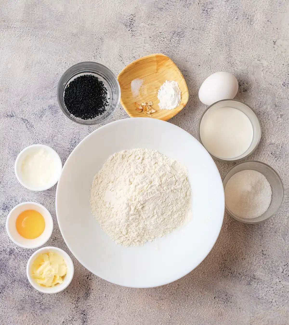 Flour, sugar, poppy seeds, baking powder and zest, an egg, a yolk, milk, cream and butter laid out for lemon poppy seed scones