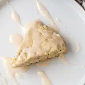 A single glazed wedge of lemon poppy seed scones on a white plate