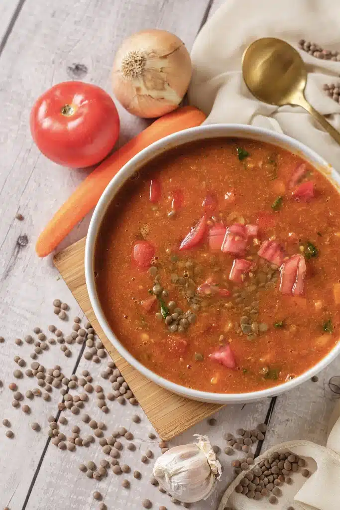 Lentil soup seen from directly above in a white bowl on a wooden board