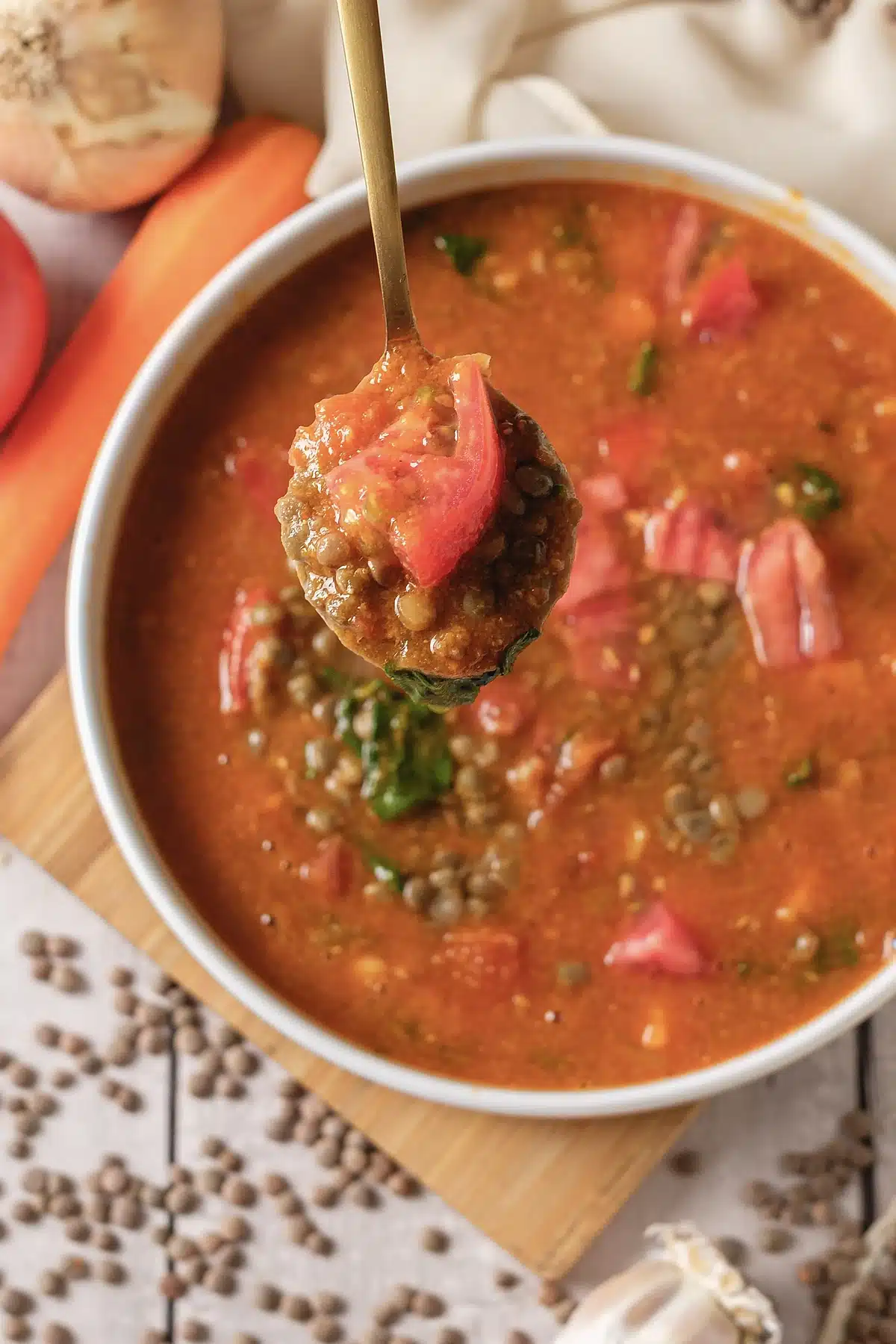 Close view of a spoonful lifted above the bowl, tomato and greens visible