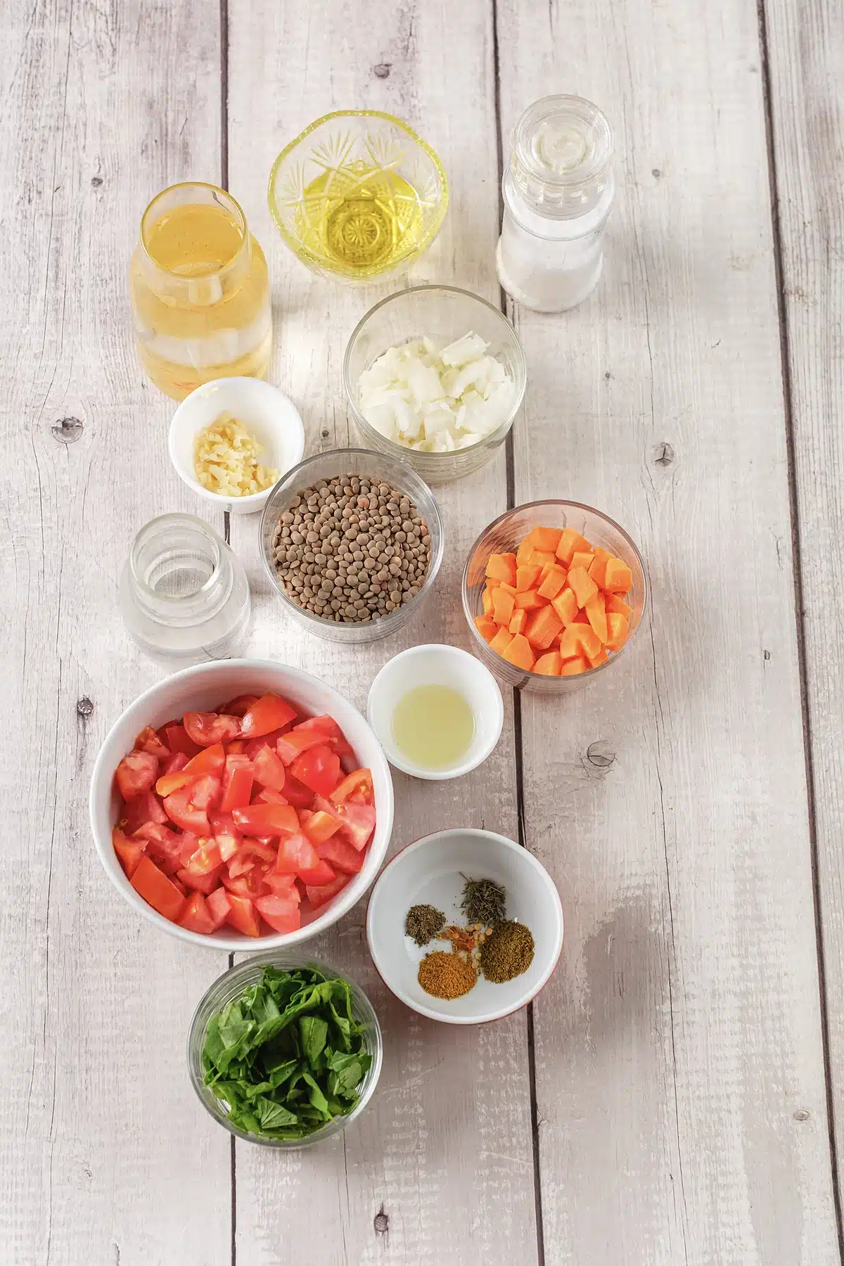 Brown lentils, diced tomato, carrot, onion, spinach and spices in small glass bowls