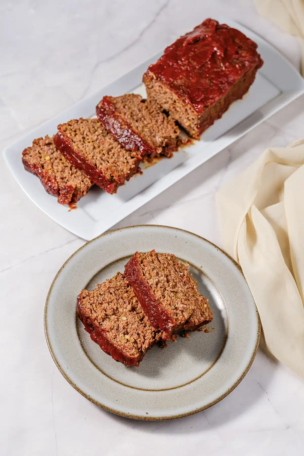 Lipton onion soup meatloaf sliced on a white platter with two slices plated