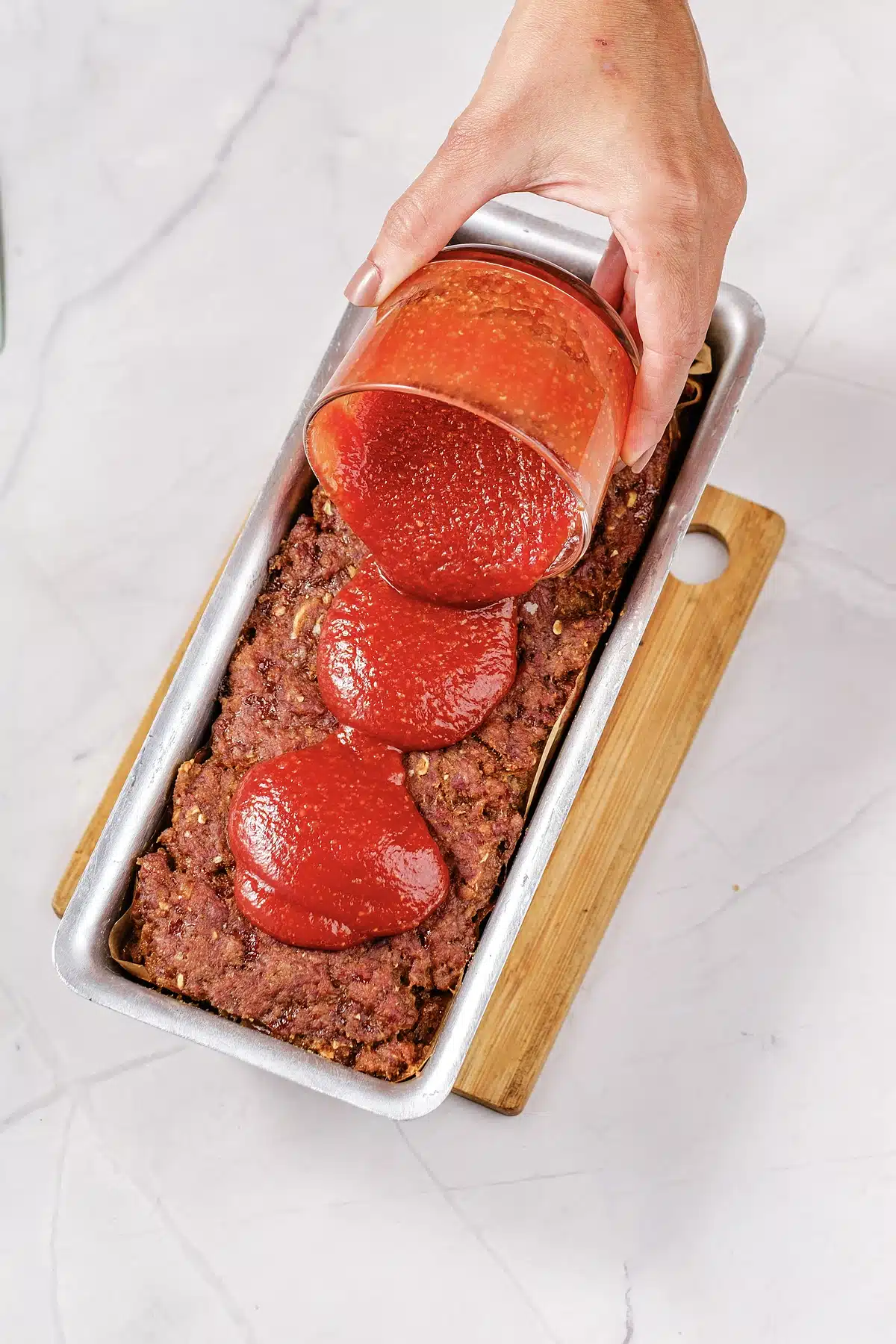 Red glaze poured over the baked Lipton onion soup meatloaf in its tin