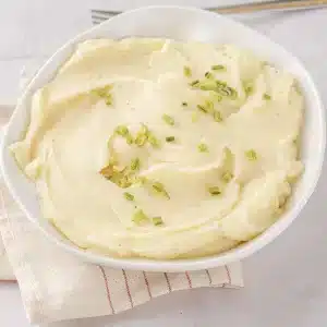 A bowl of mashed rutabaga, half-potato version, with chives and a fork