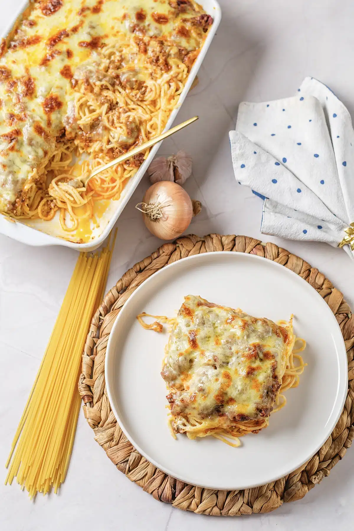 Million dollar spaghetti plated on a woven mat with the dish behind