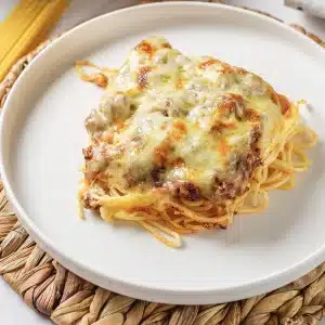 A single square of million dollar spaghetti on a white plate