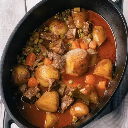 The thickened gravy around potato halves, carrots and chunks of meat in the black pot