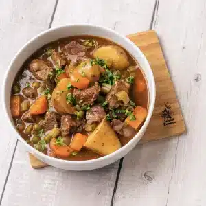 A single bowl of homemade beef stew on a wooden board