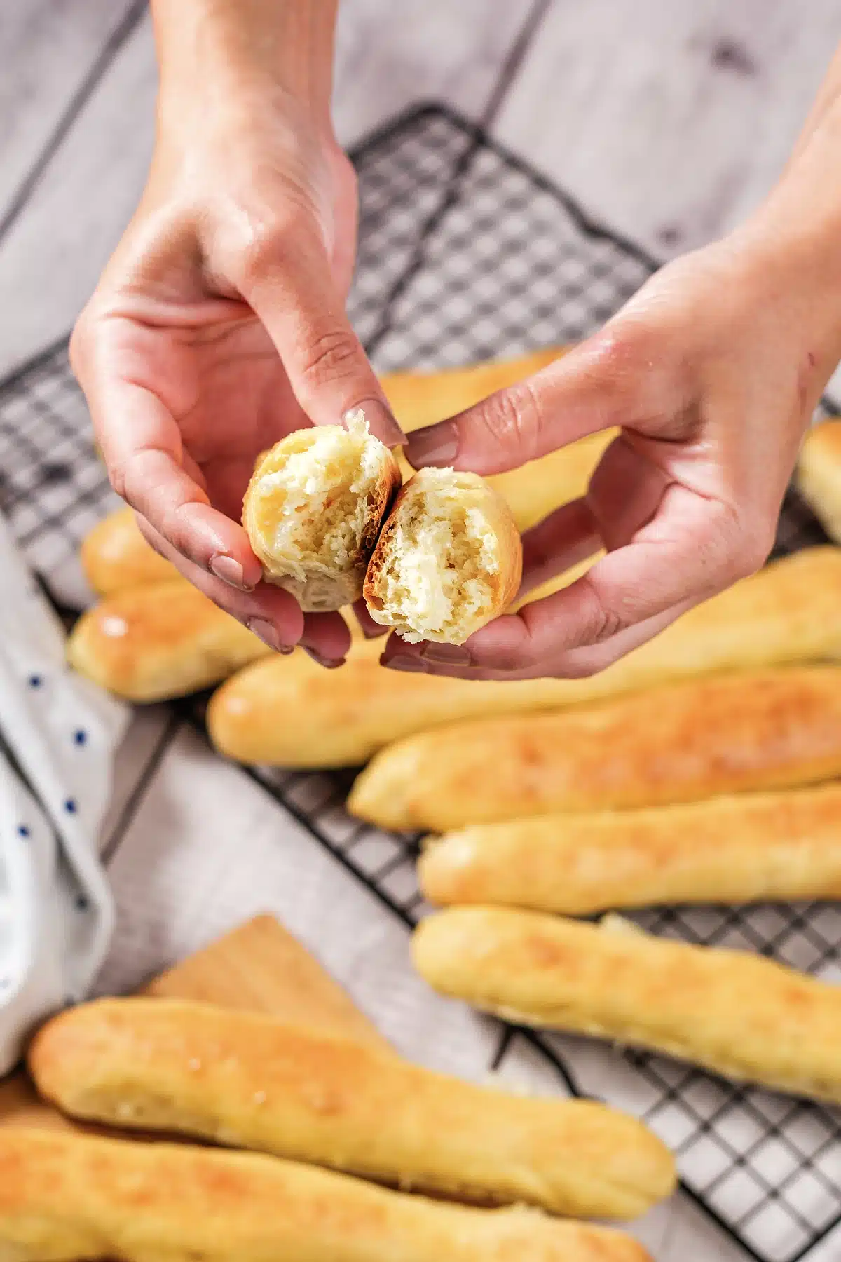 Hands tearing a warm baton open to show the soft crumb inside