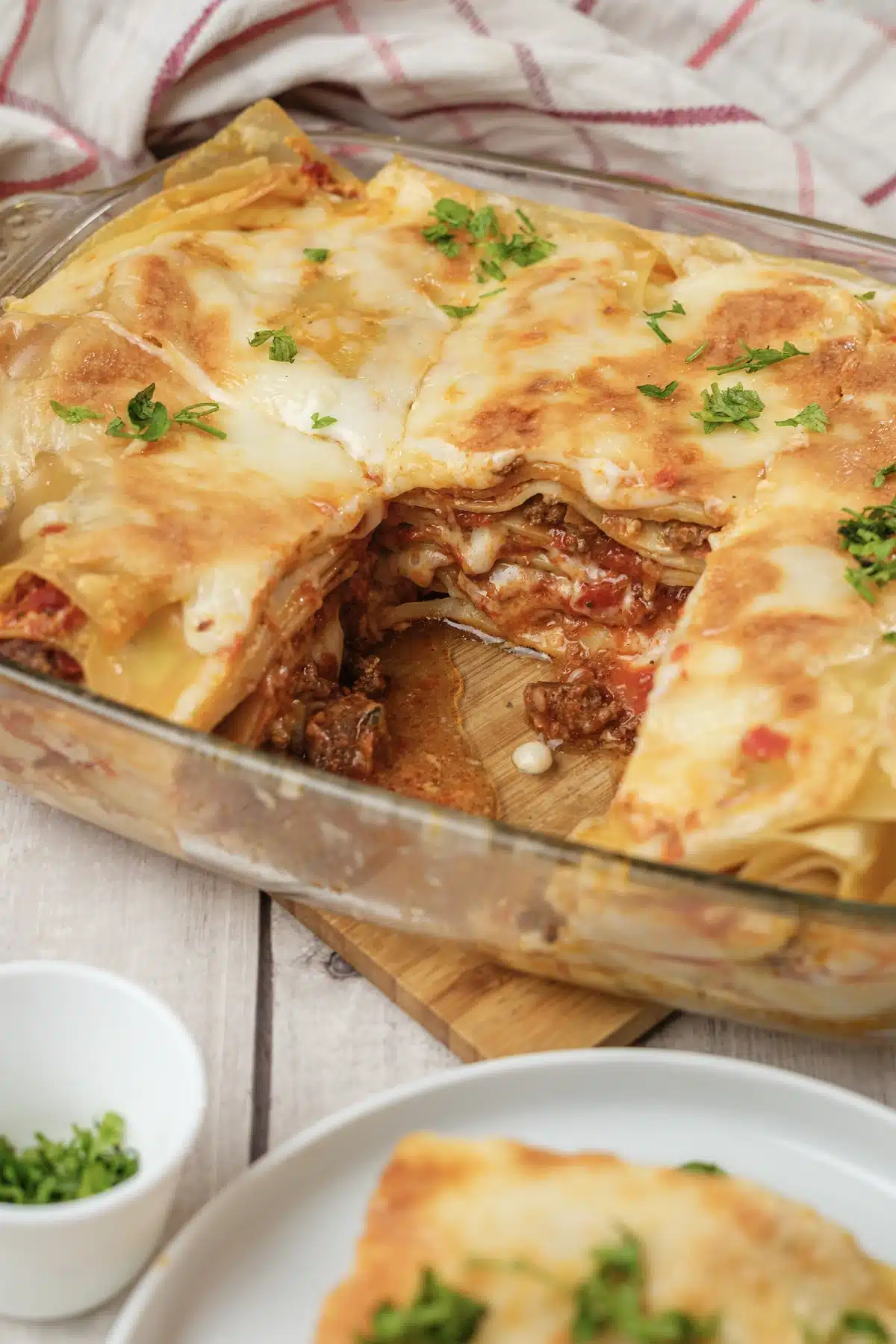 Olive Garden lasagna in a glass dish with one square removed and parsley on top