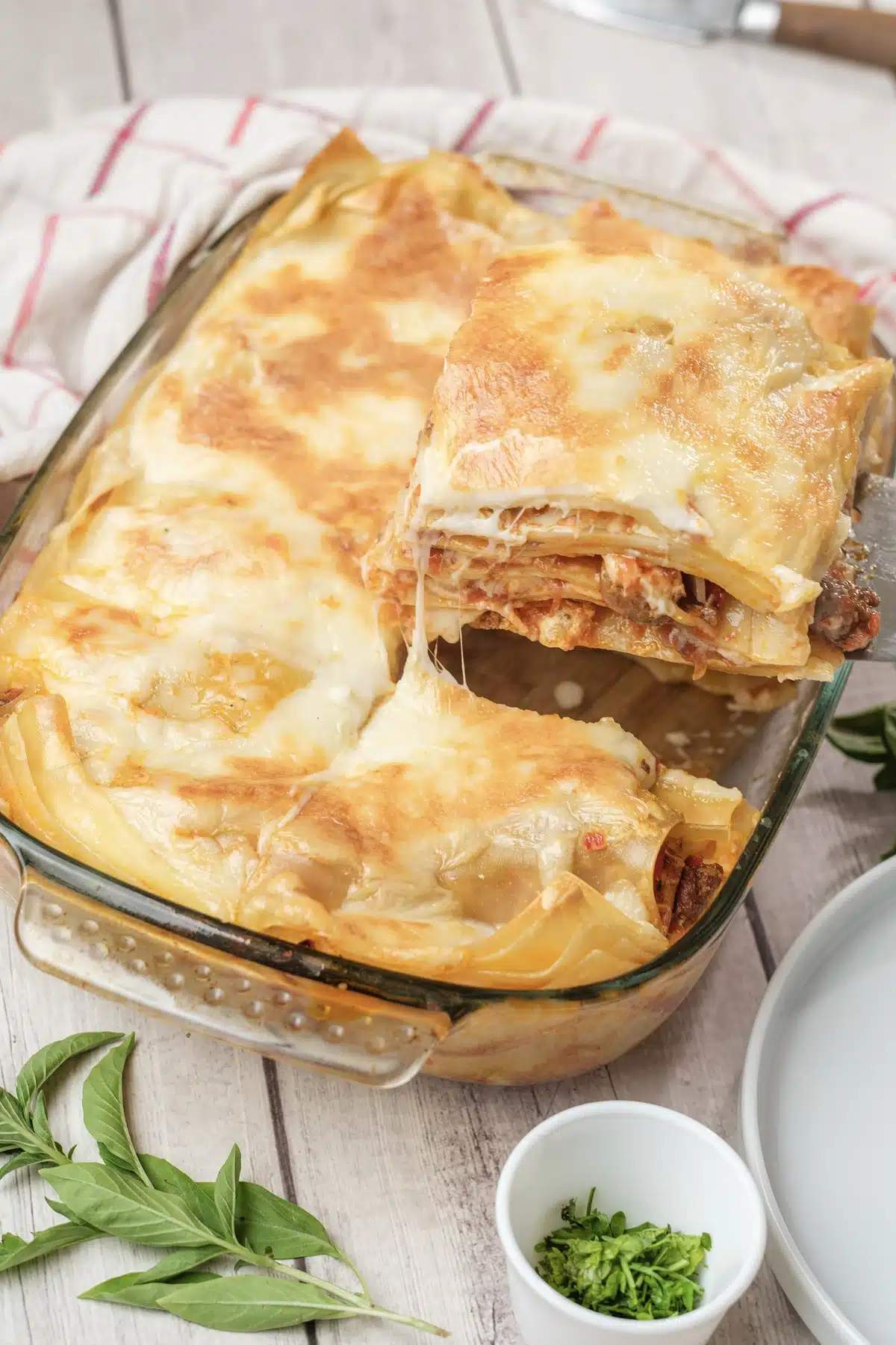 A square of Olive Garden lasagna held up on a spatula over the baking dish