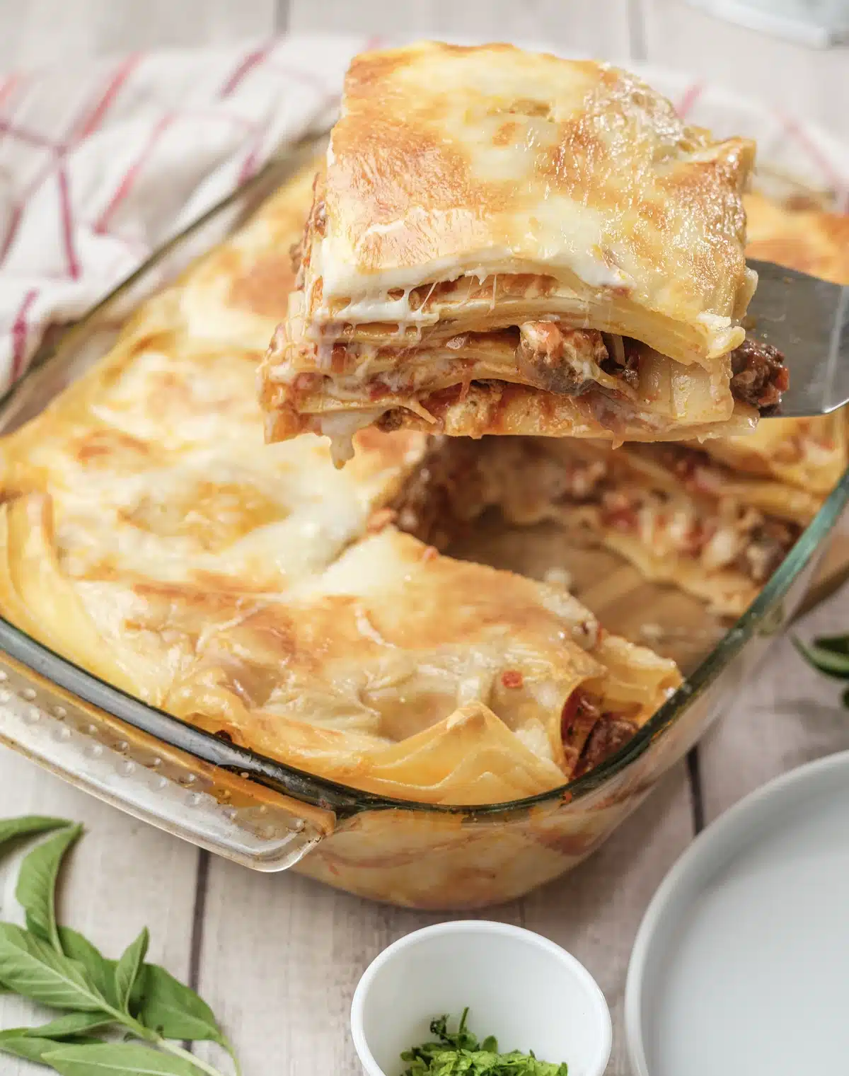 A spatula lifting a corner piece to show the stacked layers and stretched cheese