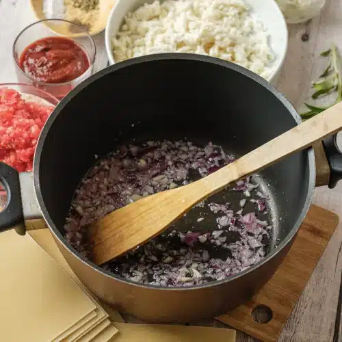 Diced red onion softening in olive oil in a dark pot