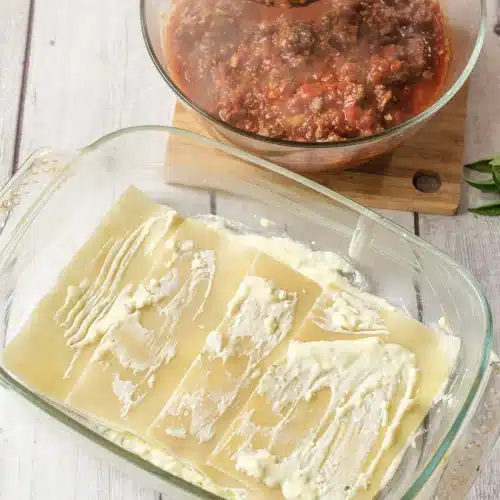 Ricotta filling spread over three flat noodles in the glass dish