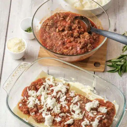 Shredded mozzarella scattered over the layer of meat sauce