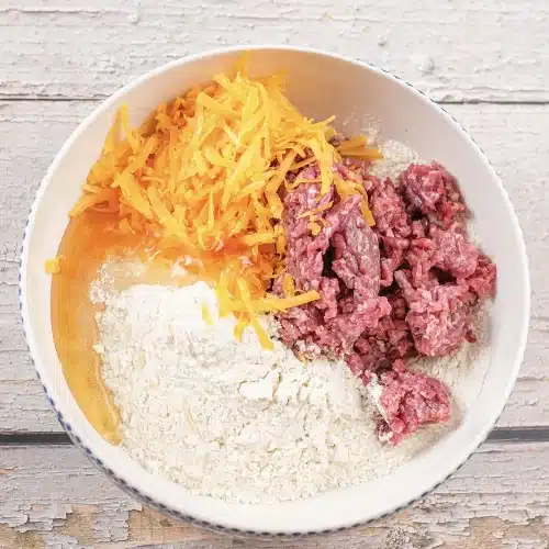The bowl of dry mix, cheddar and ground meat before it is worked together