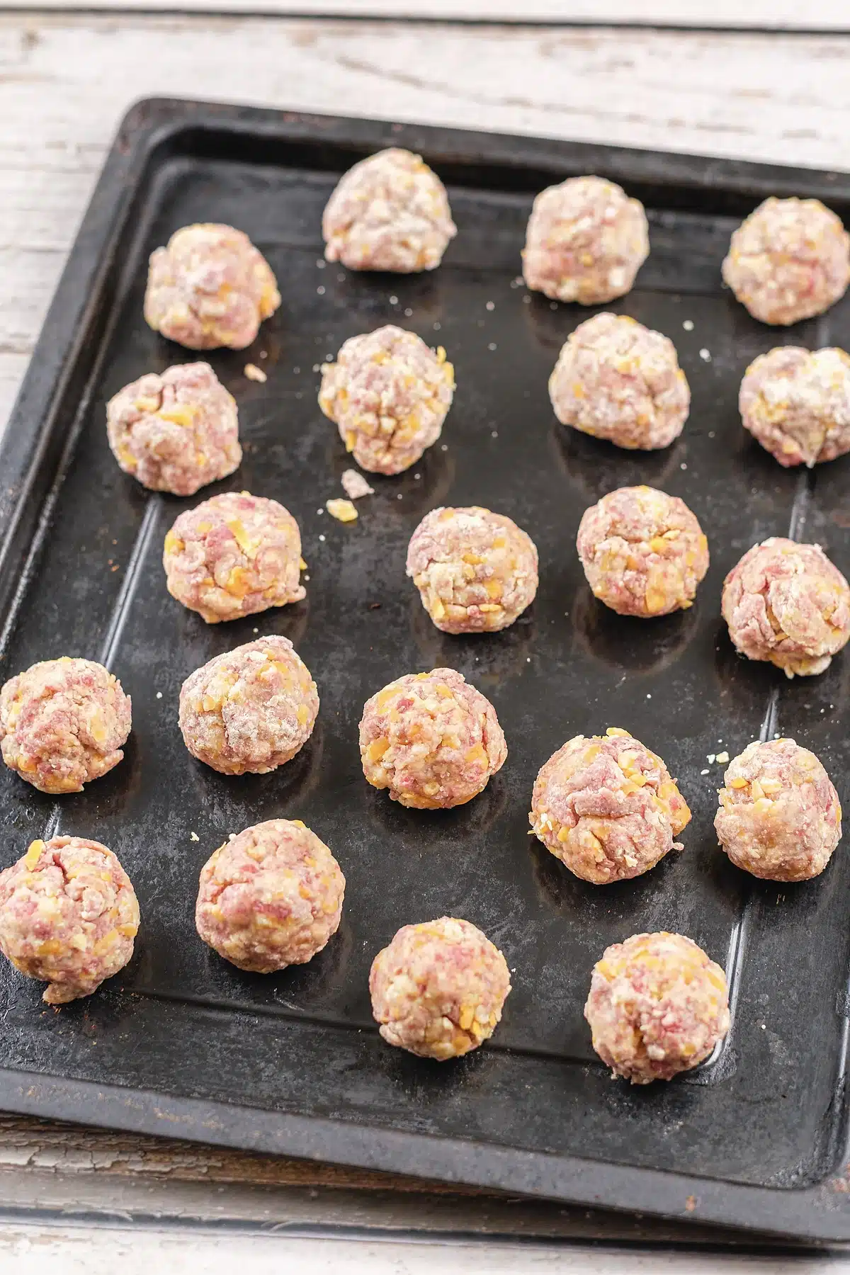 Raw rounds spaced out on a dark baking tray before going in the oven