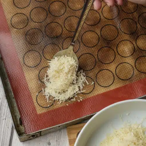 A spoonful of shredded cheese dropped onto a silicone baking mat