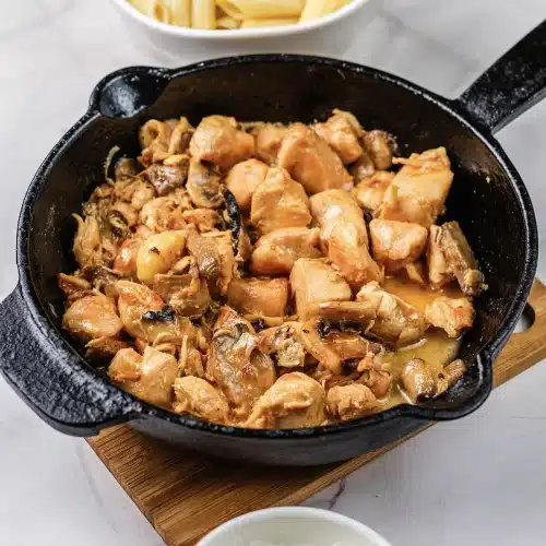 Seared chicken and mushrooms glossy with sauce in a cast iron skillet
