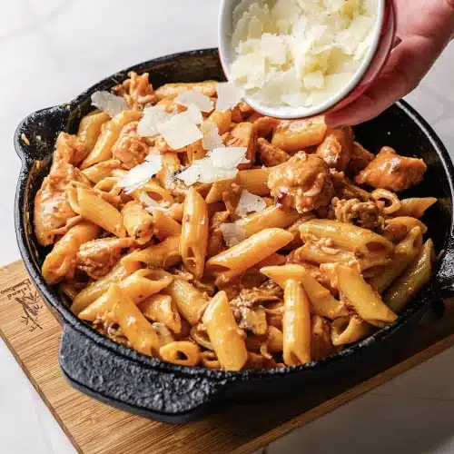 Shaved cheese tipped over the finished skillet from a small bowl