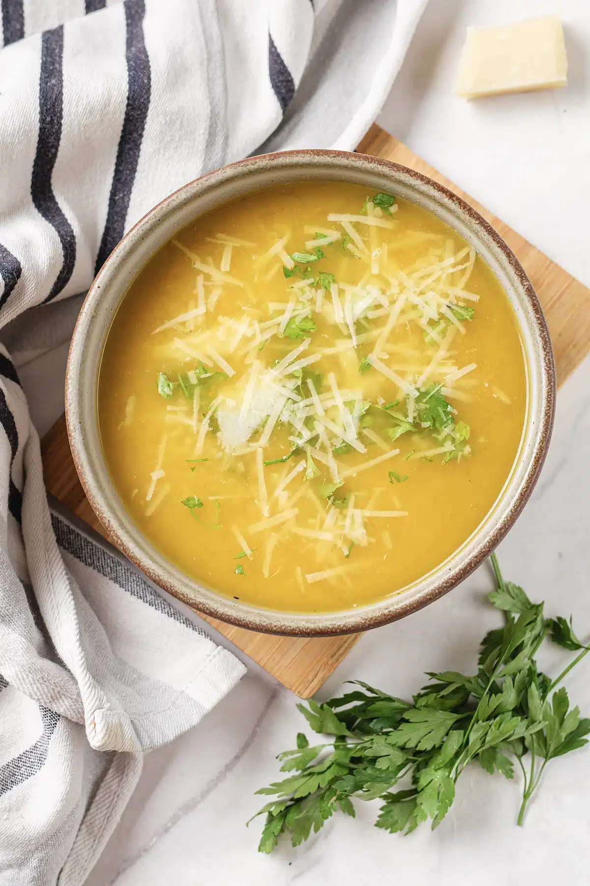 Pastina soup seen from above with parsley and shaved cheese on top
