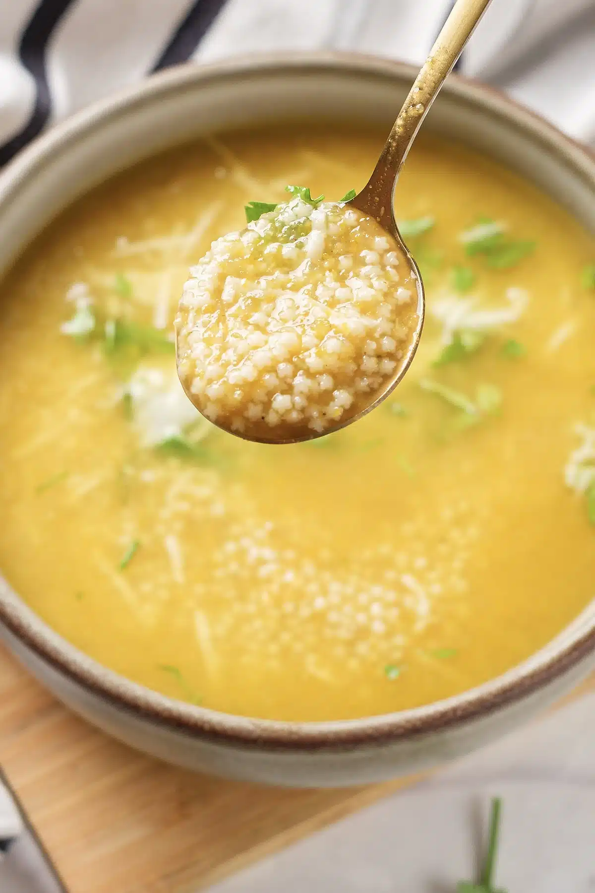 Pastina soup with a spoonful of tiny pasta lifted above the bowl