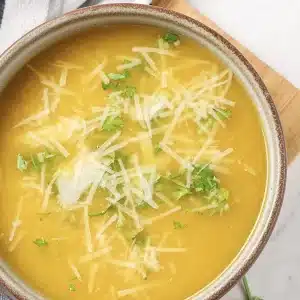 A single bowl of pastina soup topped with parsley and grated cheese