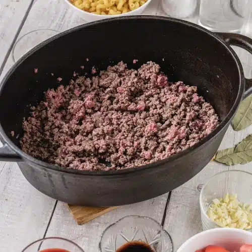 Raw ground beef breaking up in a black cast iron pot