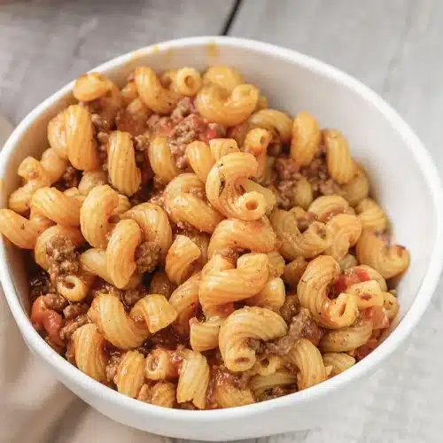 A single bowl of Paula Deen goulash on a pale wooden table