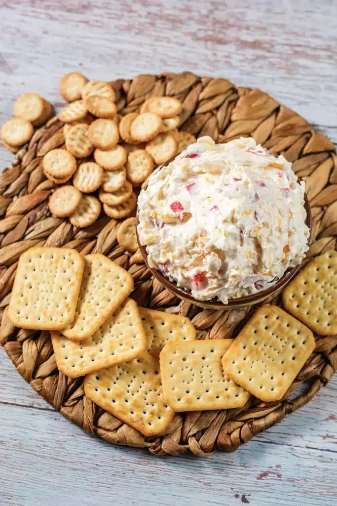 Pimento cheese seen from directly above in a dark bowl on a round woven charger