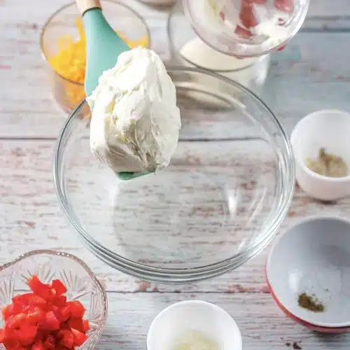 Softened cream cheese lifted into a glass mixing bowl on a spatula