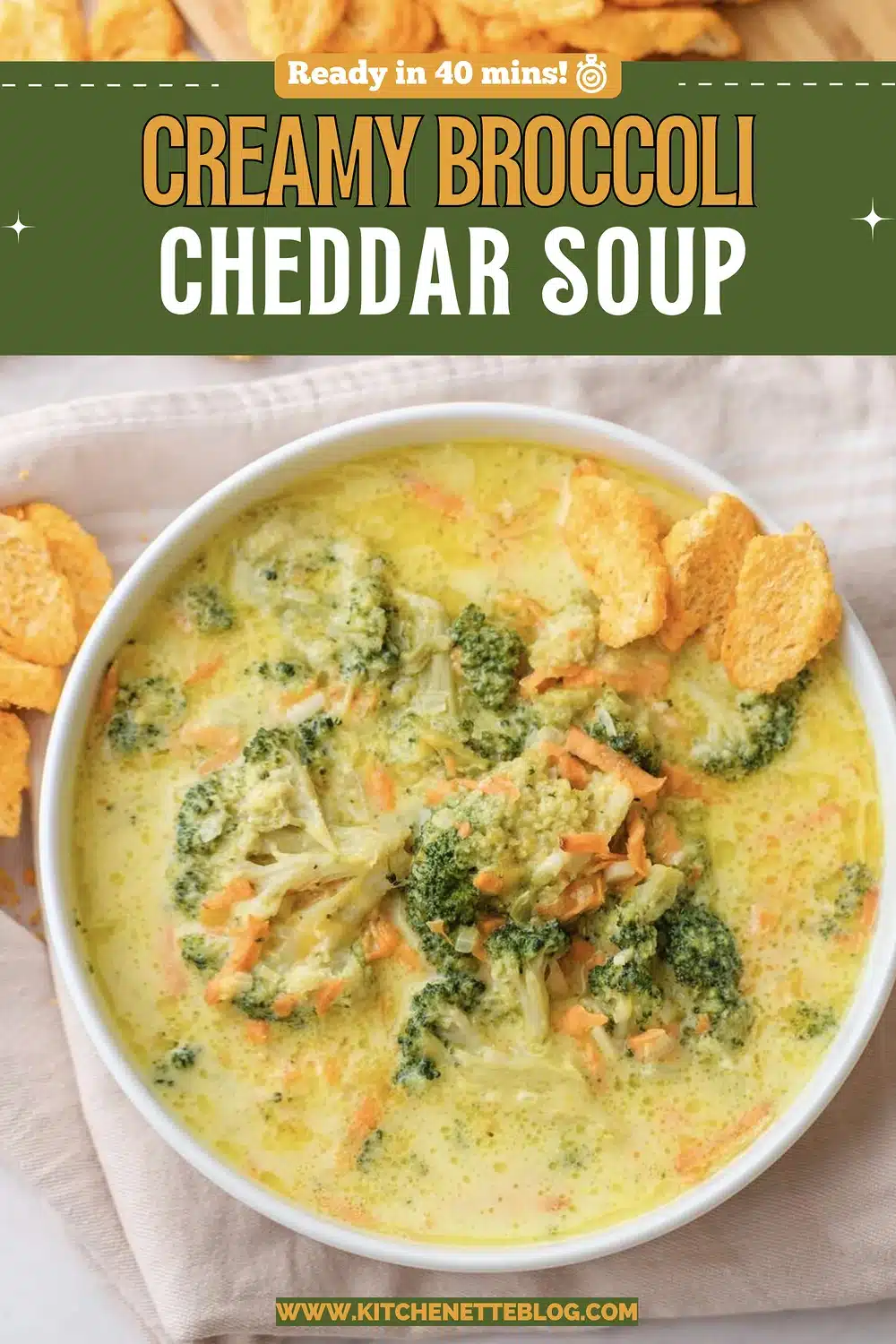 A white bowl of yellow soup with green florets and shredded carrot, topped with orange crackers