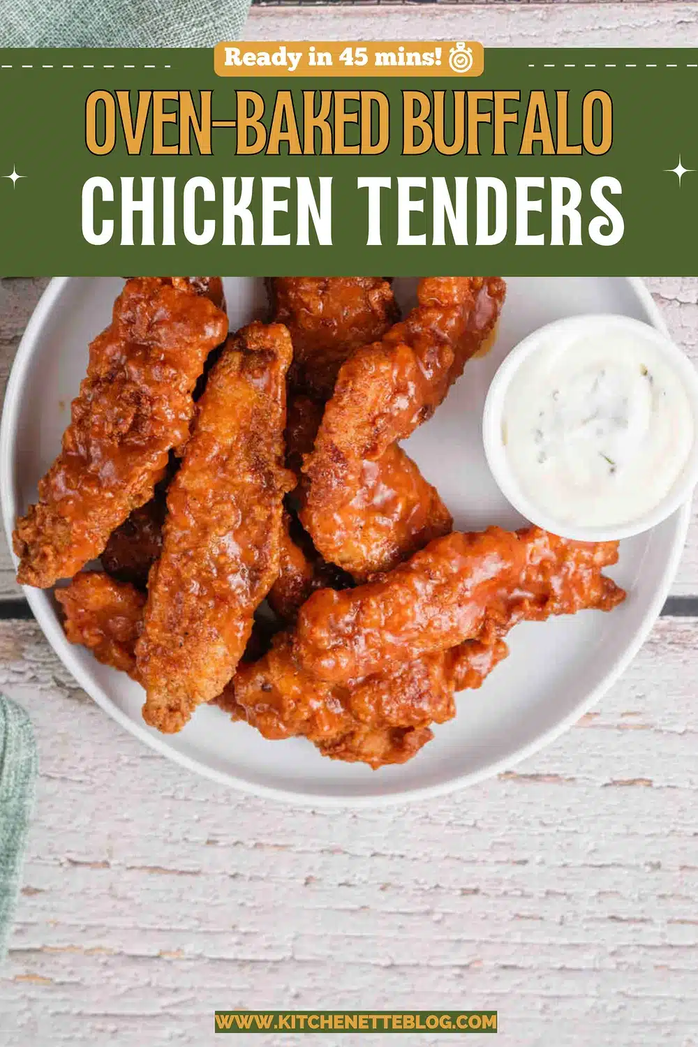 A plate of crispy sauced strips beside a cup of ranch on a white wooden table