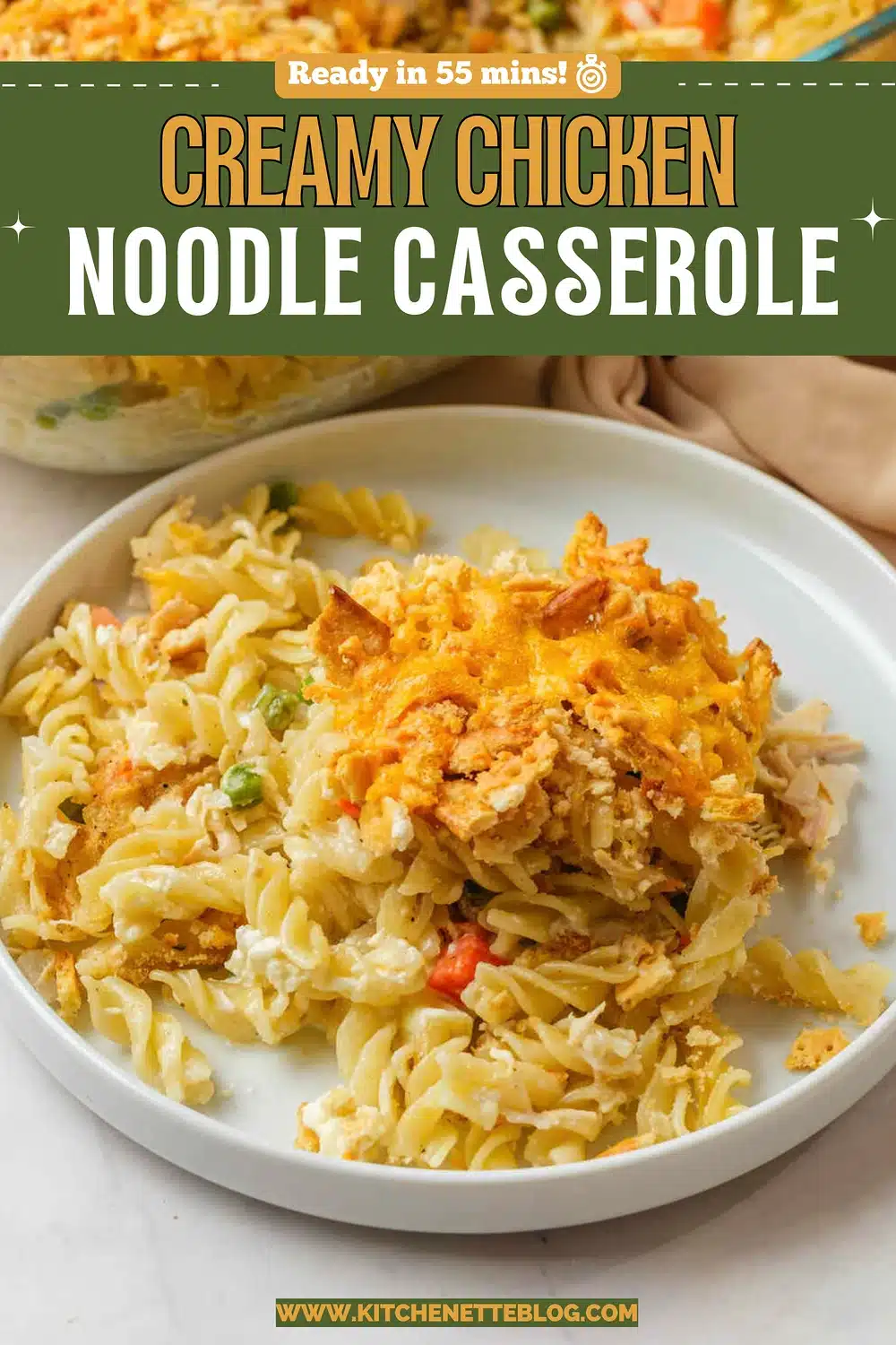 A plate of spiral pasta in a cream sauce with a golden cracker and cheese topping, with the baking dish behind