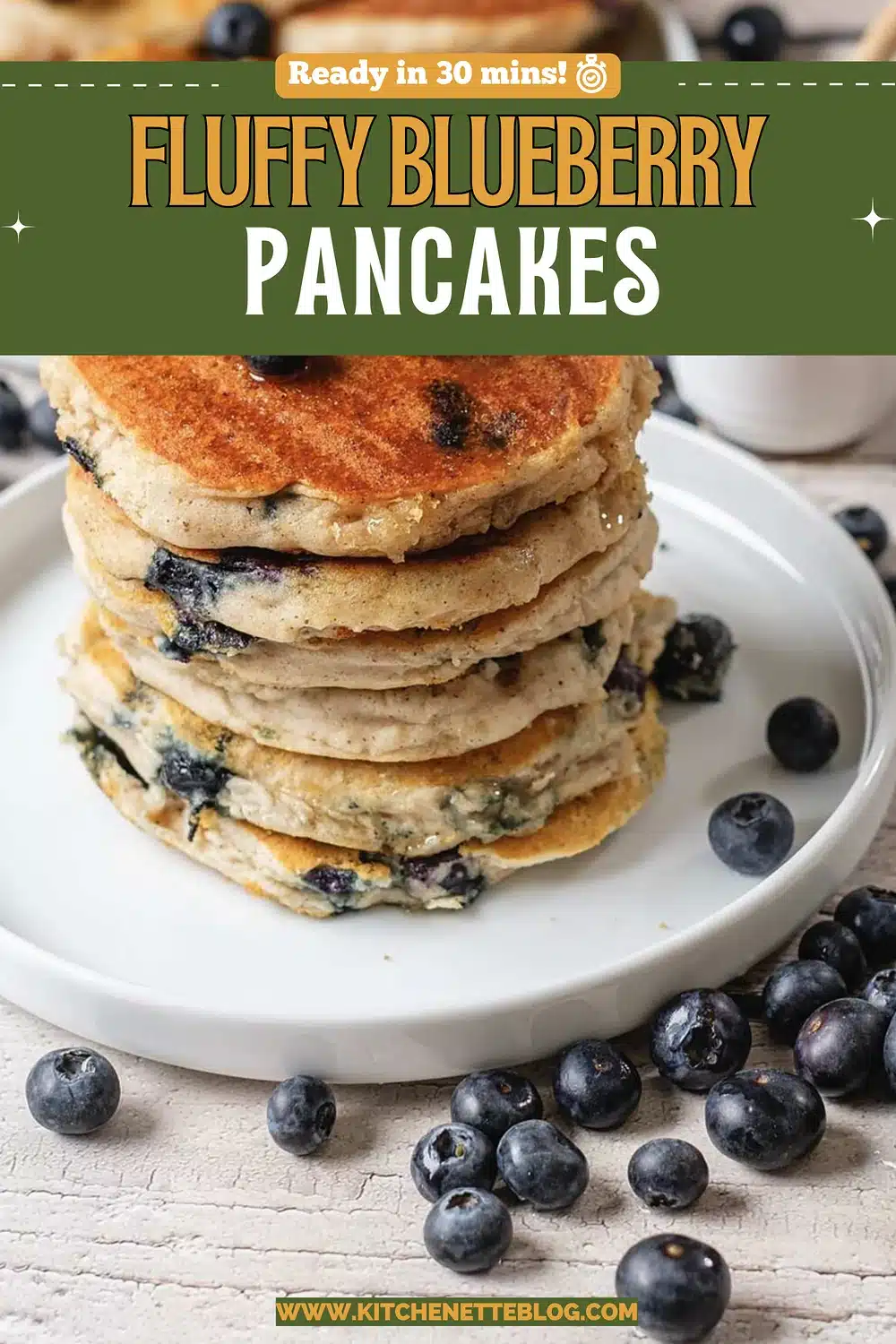 A tall stack of golden griddle cakes on a white plate with scattered berries