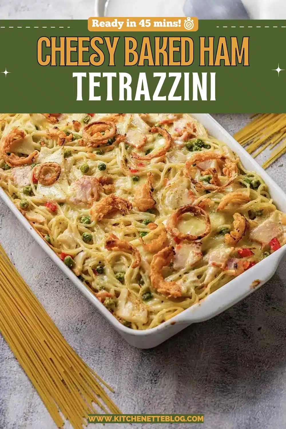 A white dish of creamy spaghetti casserole with peas and crisp onions