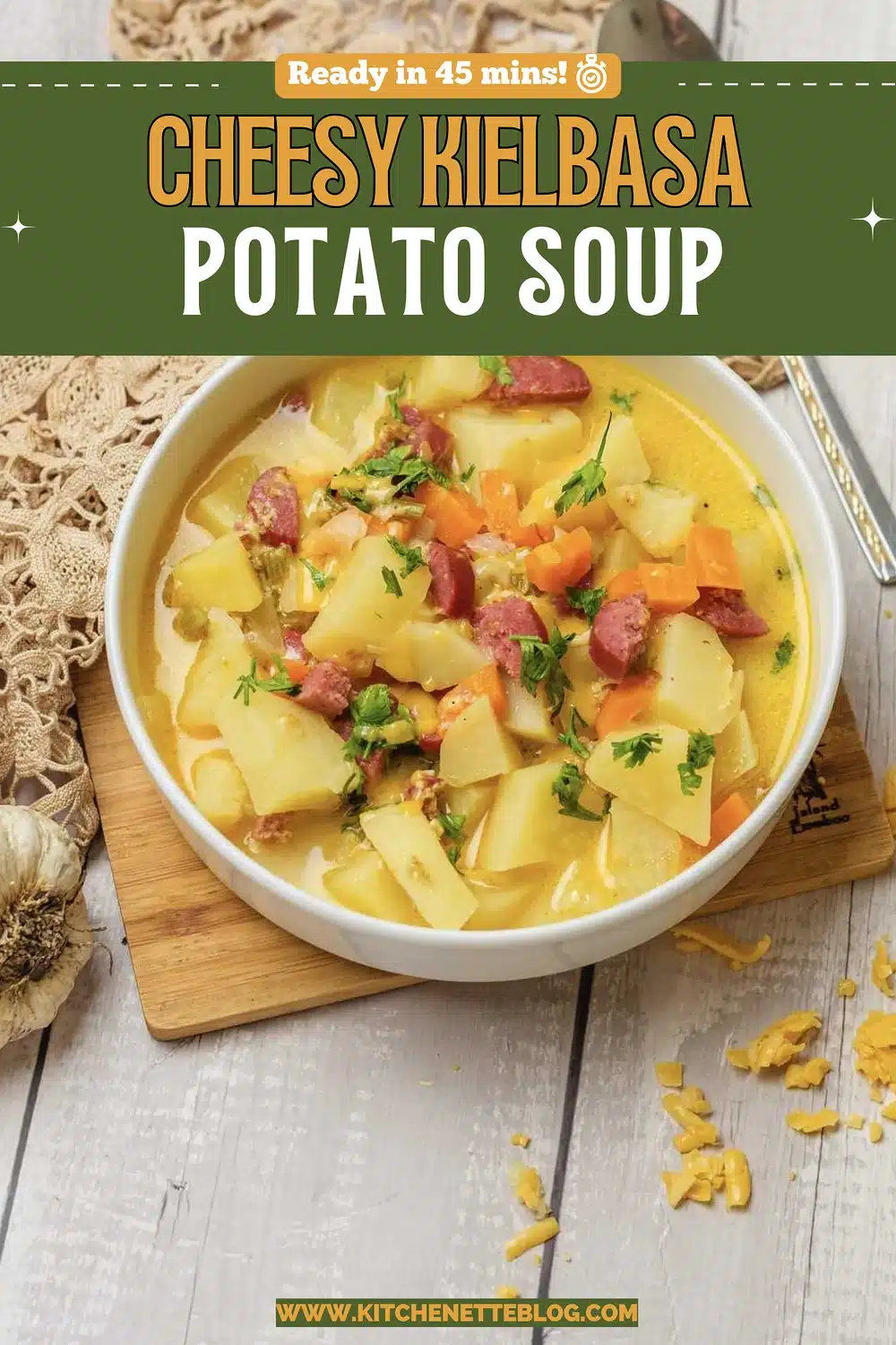 A white bowl of golden broth with big chunks of Yukon Gold, sausage pieces, diced carrot and parsley