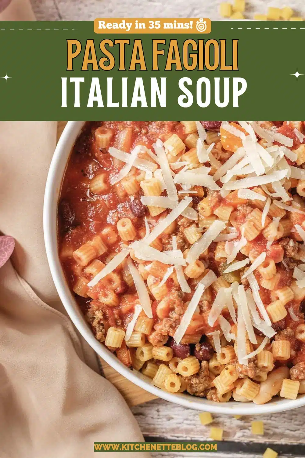 A white bowl of tomato broth with small tubes, beans and shredded cheese
