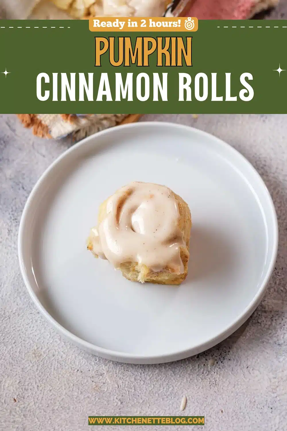 A frosted roll on a white plate with the baking dish behind