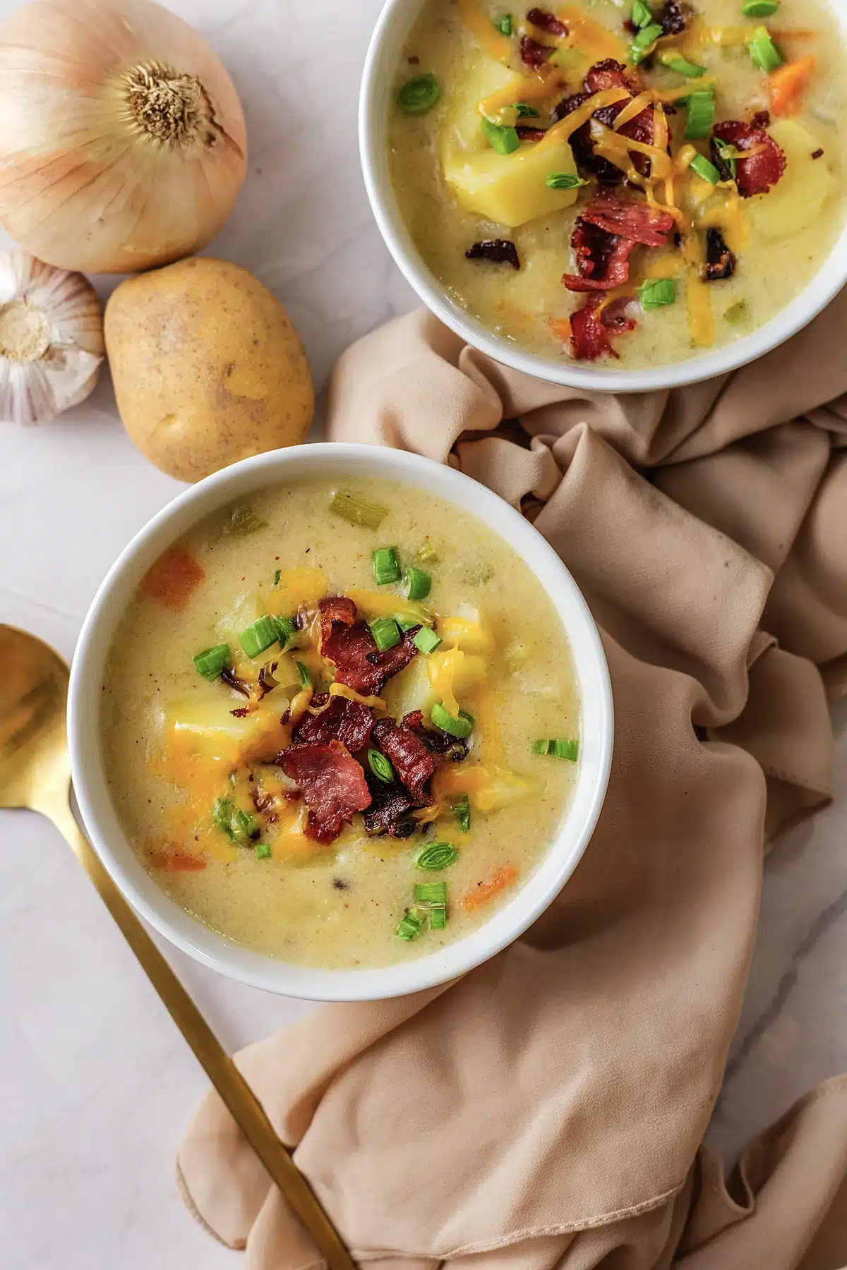 A close view of a white bowl with bacon, melted cheddar and green onion