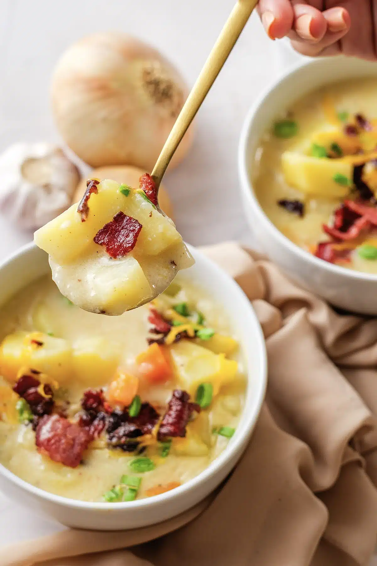A spoonful of creamy potato soup lifted above the bowl