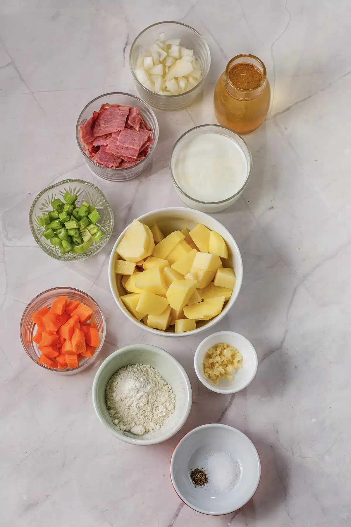 Diced potatoes, bacon, celery, carrot and cheddar laid out for potato soup