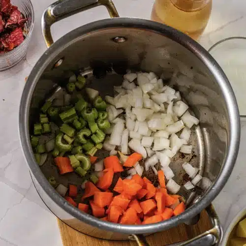Onion, celery and carrot softening in the rendered bacon fat