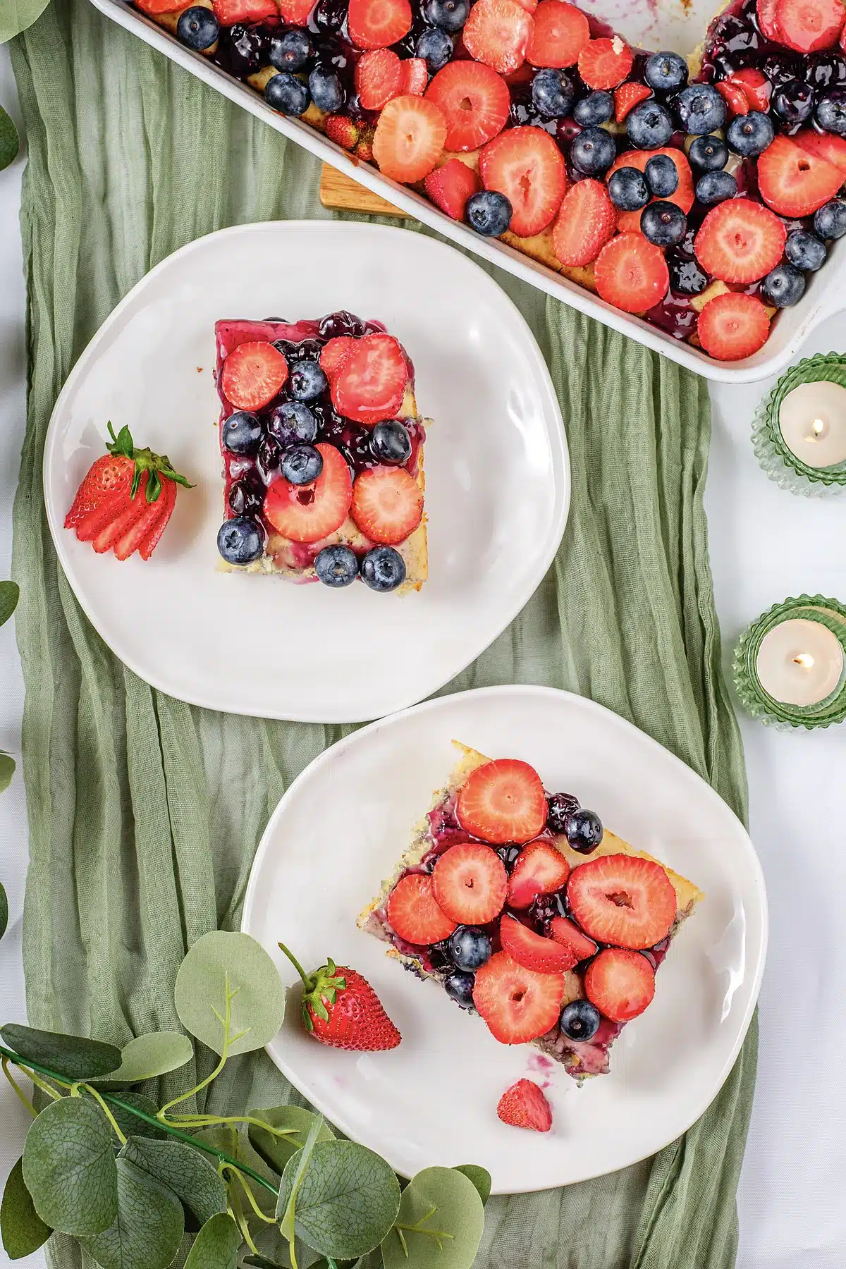 Easy sheet pan pancakes plated beside the dish of strawberries and blueberries