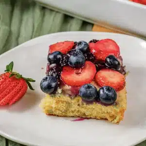 One square topped with strawberries and blueberries on a white plate